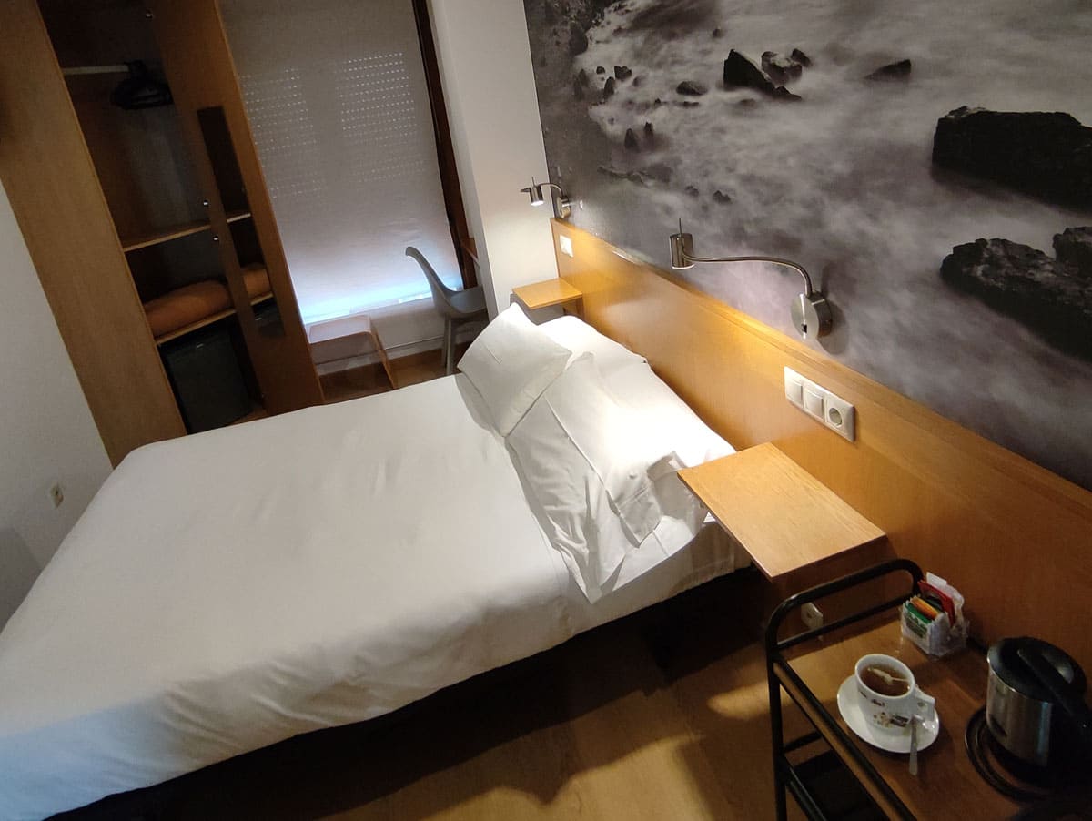 Habitación doble pequeña con cama de 1,35 y detalle de infusión junto a la cama